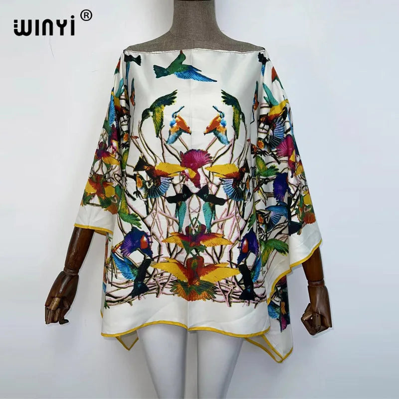 A white batwing abaya top featuring colorful bird embroidery and floral patterns.