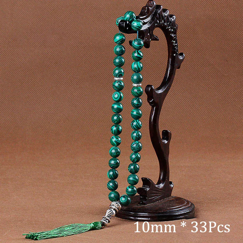A dark wooden stand holds a necklace of green beads and a tassel.