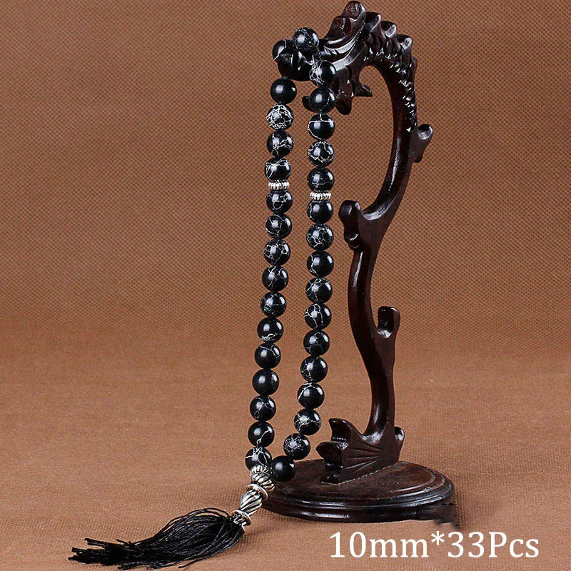 A dark brown wooden prayer bead necklace with black agate beads and a tassel displayed on a stand.