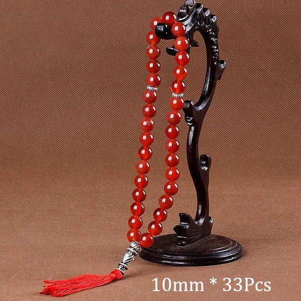 Black agate prayer beads on a stand with a red tassel necklace