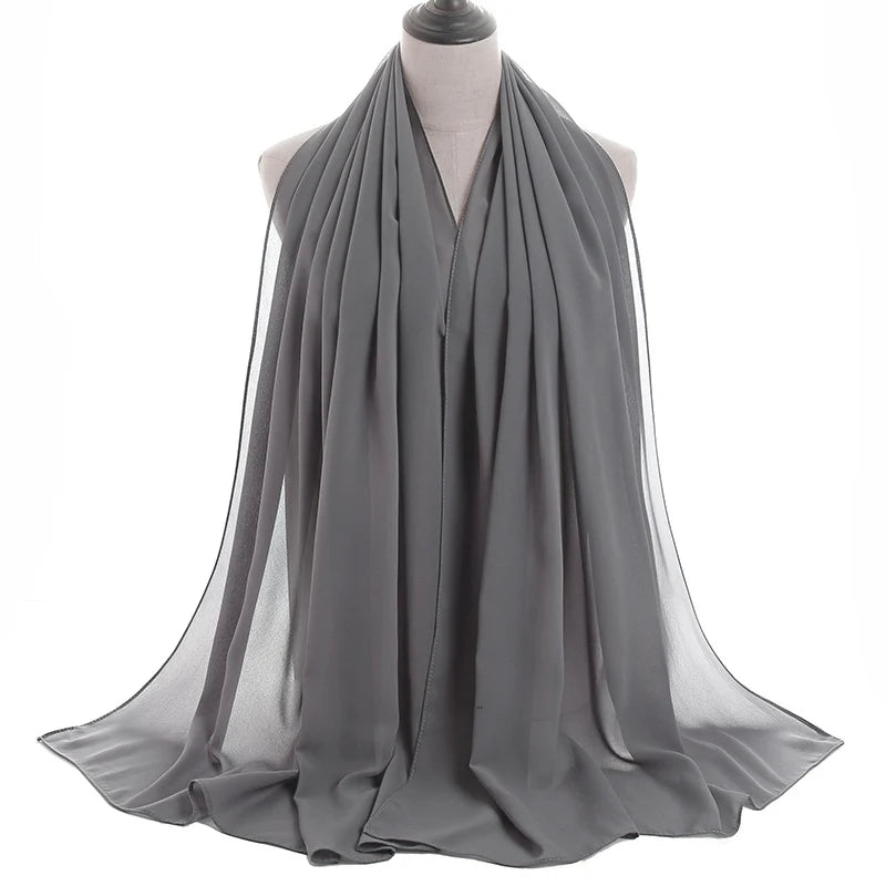 Un pañuelo de chifón gris drapeado alrededor del cuello y los hombros de un maniquí.