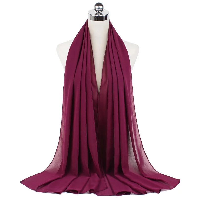 Ein tiefmagenta Chiffon-Sofachat, drapiert um den Hals einer Mannequin.