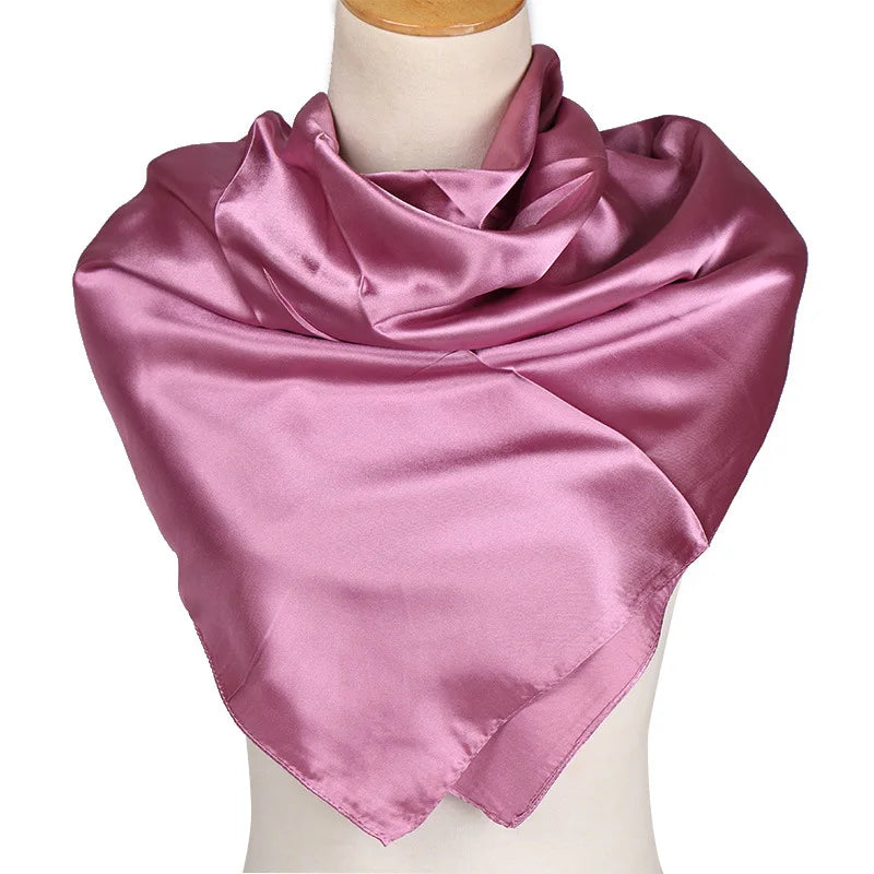 A draped solid pink silk satin hijab scarf displayed on a mannequin.