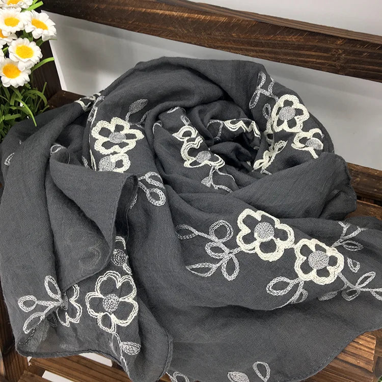 Dunkelgraves florales besticktes Wintertuch auf einer Holzoberfläche.