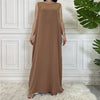 Langes, ärmelloses, braunes Kaftan-Kleid in einer weißen Paneelwand