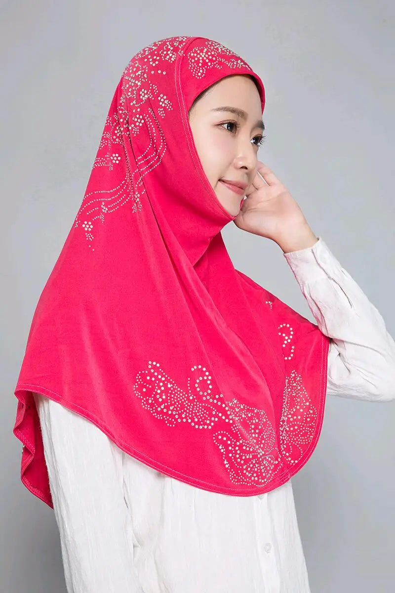 Eine Frau trägt einen leuchtend pinken Strass-Hijabschal über einem weißen Oberteil.