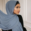 Eine Frau trägt einen hellblauen Chiffon-Hijab über Kopf und Schultern.