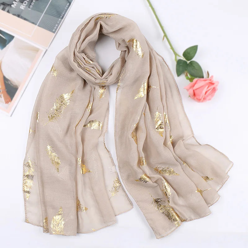 Beige Chiffon-Hijab-Schal mit goldenen Glitzerfederakzenten auf weißem Hintergrund.