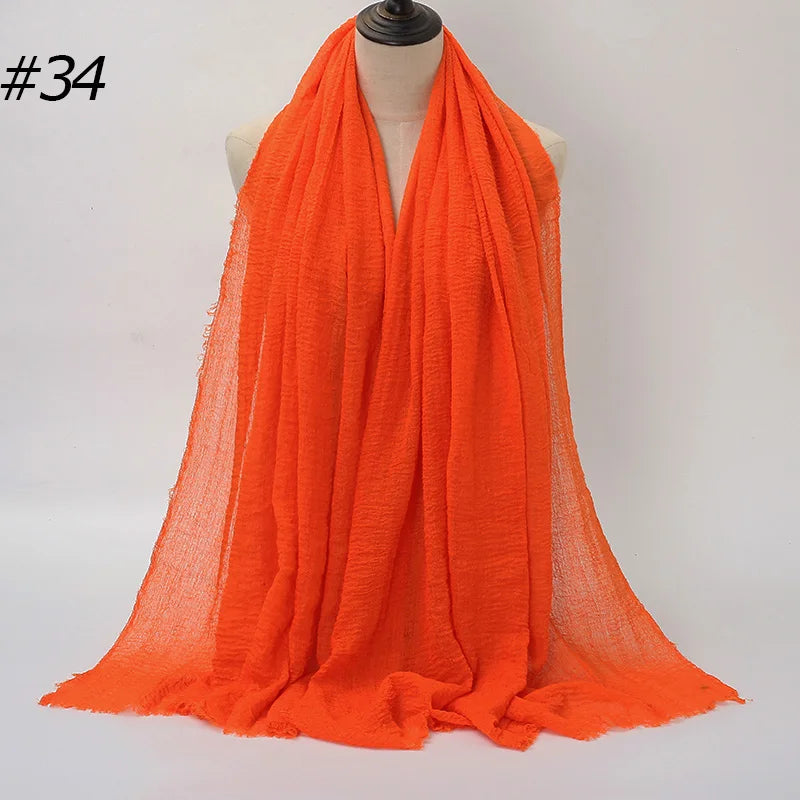 Helles orangefarbenes Crinkle-Baumwoll-Hijab-Tuch über einem Mannequin-Hals drapiert.