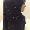 Un pañuelo de hijab de cuentas morado oscuro drapeado sobre la cabeza y el hombro de una modelo.