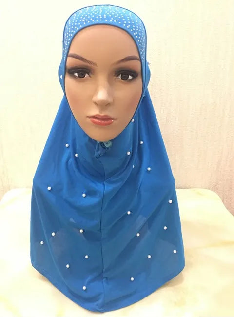 A woman models a bright blue beaded Muslim hijab scarf draped over her head and shoulders.