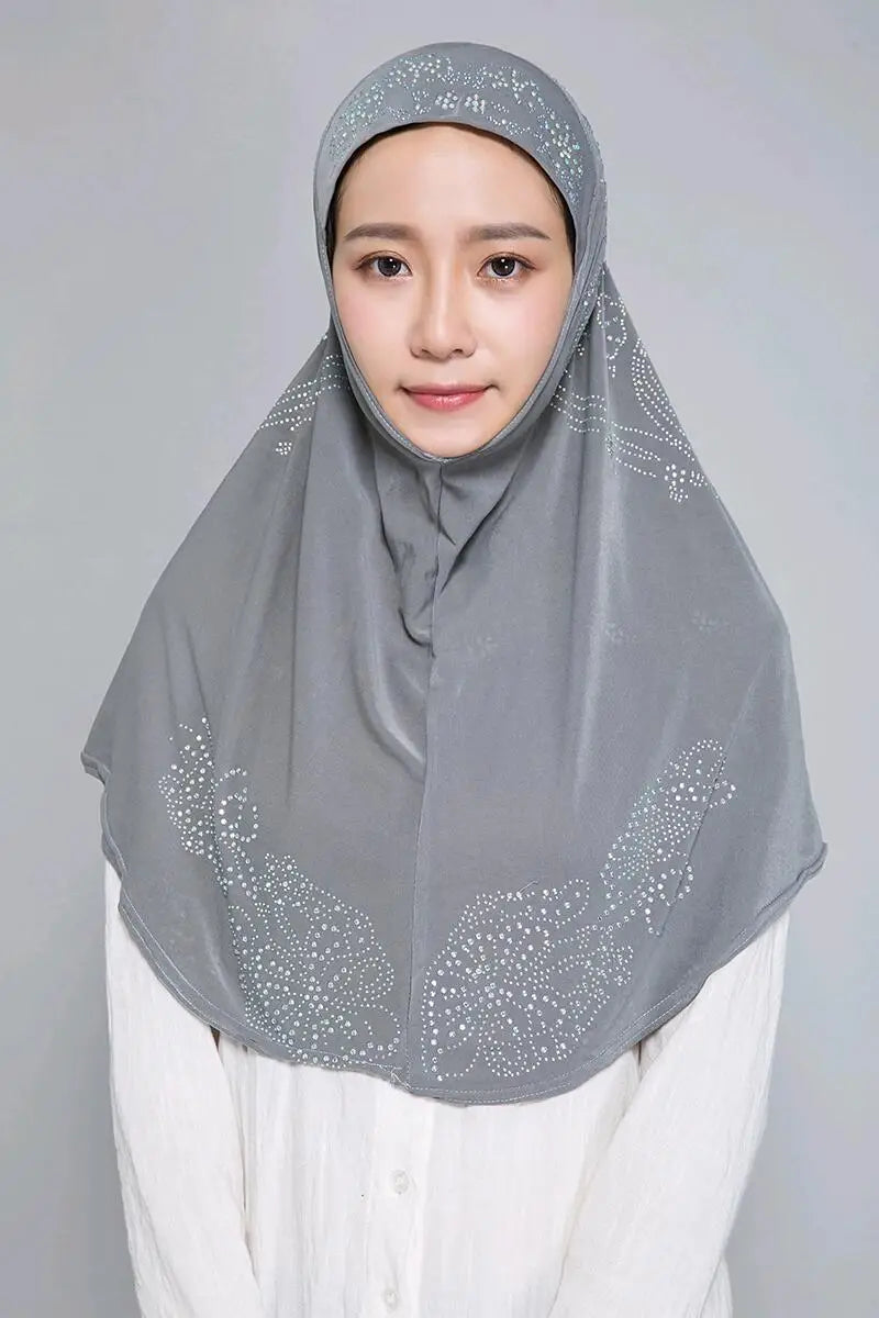 Eine Frau trägt einen eleganten grauen Diamant-Hijab über einem weißen Oberteil.
