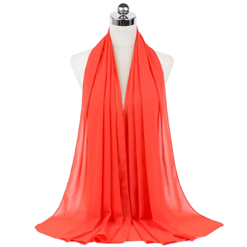 Un pañuelo de chifón naranja brillante drapeado alrededor del cuello de un maniquí.