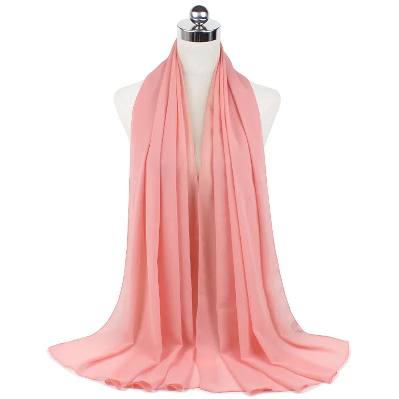 Pañuelo de chifón rosa coral fluído drapeado alrededor del cuello de un maniquí.