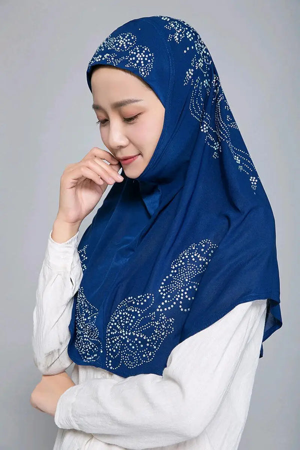 A woman wearing a royal blue rhinestone Muslim hijab scarf and white top.