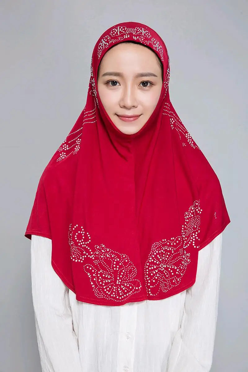Eine Frau trägt einen roten Diamant-Hijabschal über einem weißen Oberteil.