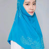 Eine Frau trägt einen leuchtend blauen Diamant-Hijabschal über einem weißen Oberteil.