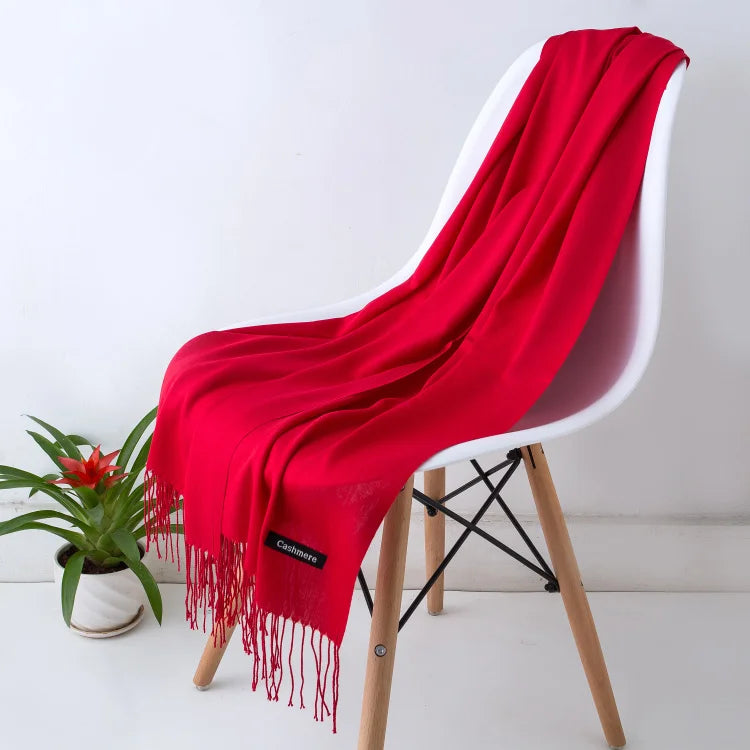 Una vibrante bufanda de cachemira roja drapeada sobre una silla blanca.