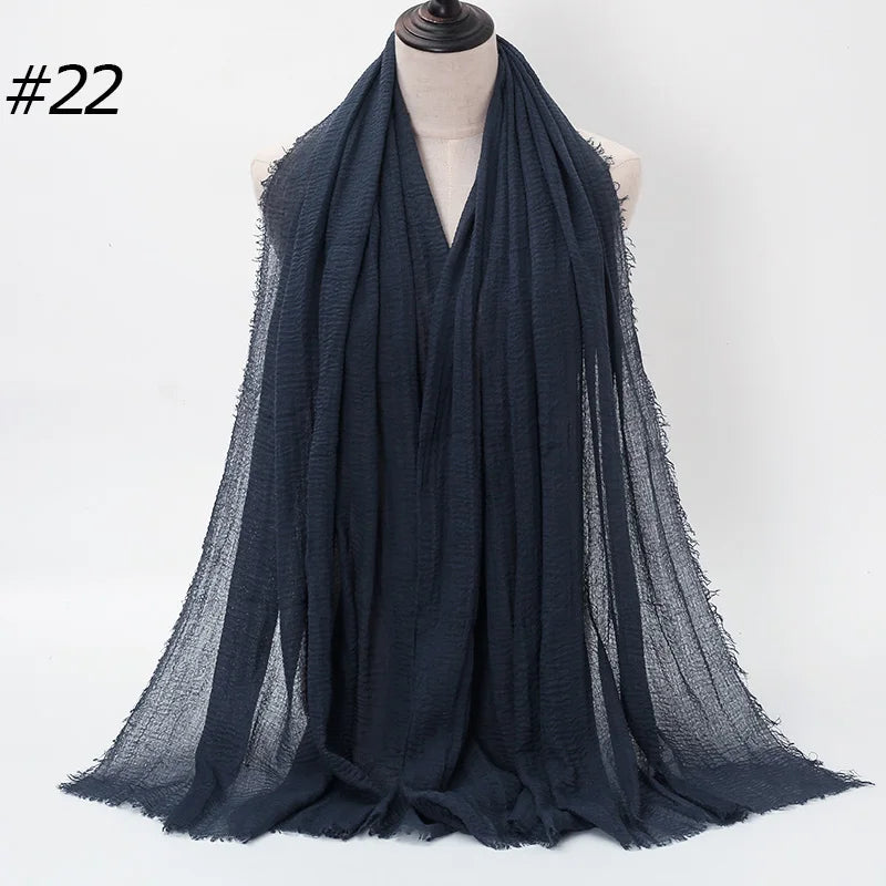 Dunkelblaue, gekräuselte Baumwoll-Hijab-Schal um den Hals eines Mannequins drapiert.
