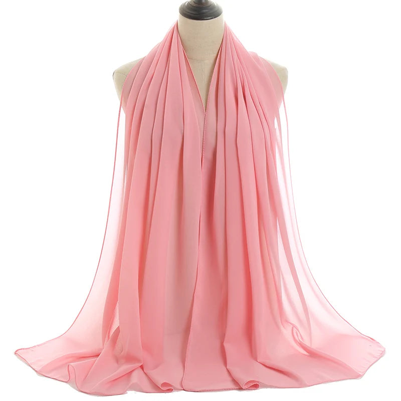 Un pañuelo de chifón rosa fluído drapeado alrededor del cuello y los hombros de un maniquí.