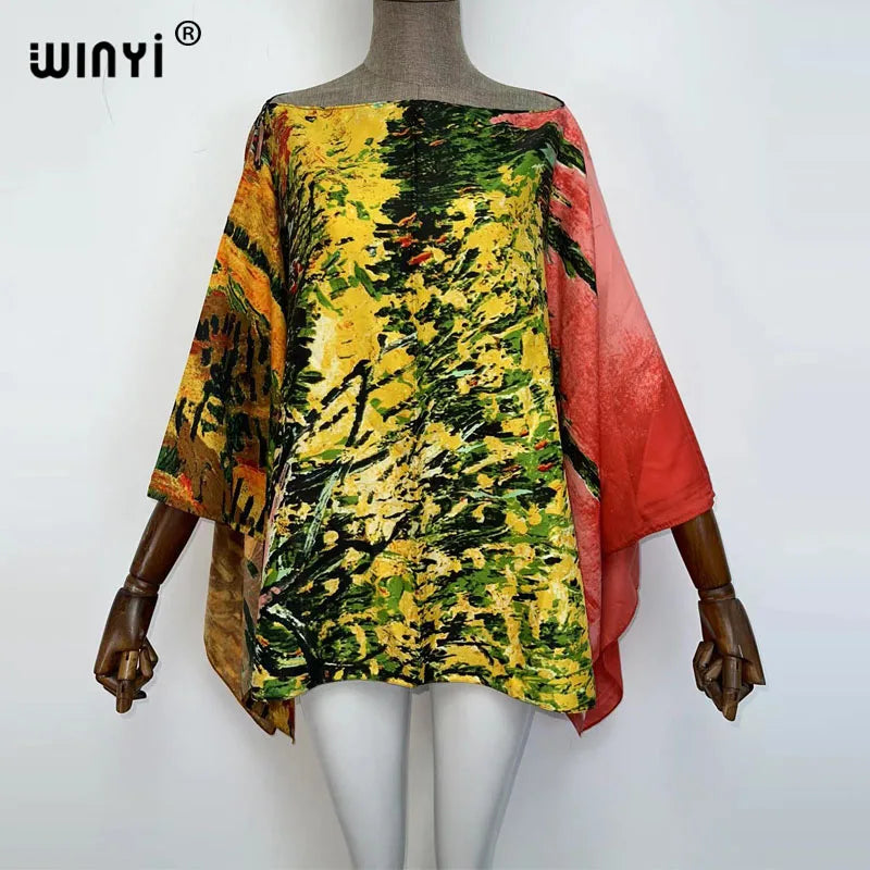 A model is wearing a yellow and green patterned batwing abaya top with orange trim.