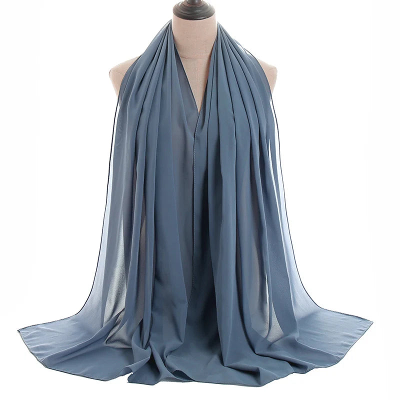 Un pañuelo de chifón azul polvoriento y fluido drapeado alrededor del cuello de un maniquí.