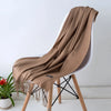 Una estola de cachemira beige drapeada sobre una silla blanca con patas de madera.