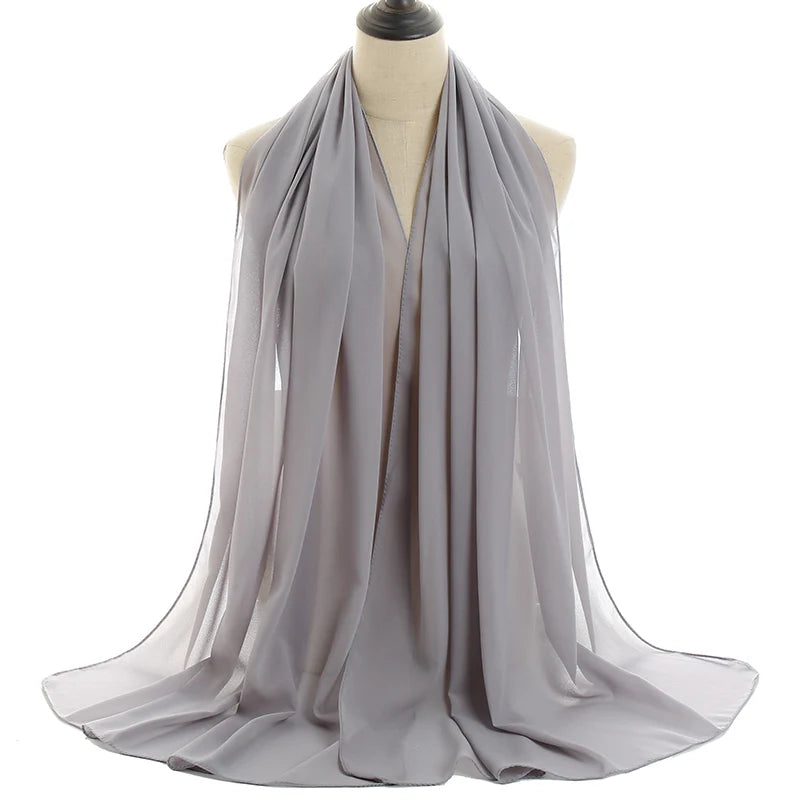 Un pañuelo de chifón gris fluido drapeado alrededor del cuello de un maniquí.