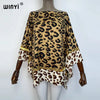 A woman models a bohemian summer batwing abaya top featuring a leopard print fabric with gold trim.