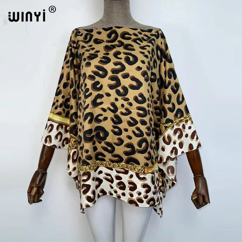 A woman models a bohemian summer batwing abaya top featuring a leopard print fabric with gold trim.