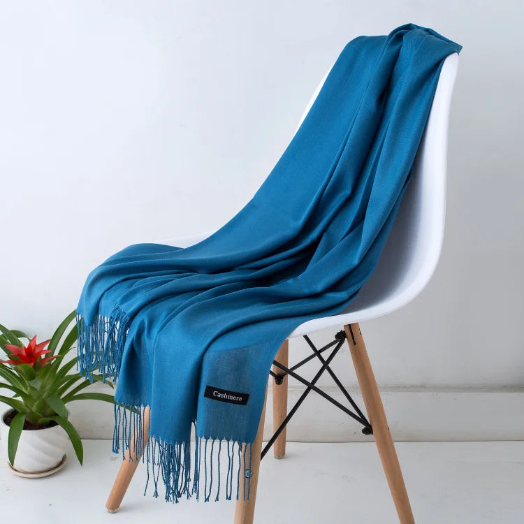 Una bufanda de cachemira azul brillante drapeada sobre una silla blanca.