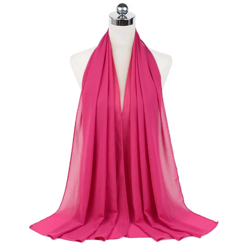 Un vibrante pañuelo de chifón rosa drapeado alrededor del cuello de un maniquí.