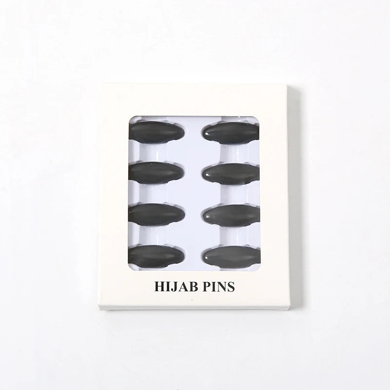 Una tarjeta blanca mostrando ocho pines y clips negros para hijab.