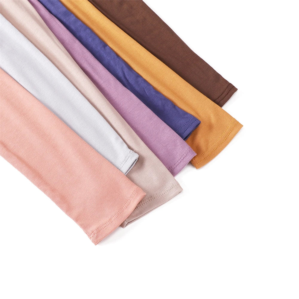 Stapel farbenfroher, dehnbare islamische Schlafarm-Cover in Rosa, Lila, Orange und Braun.