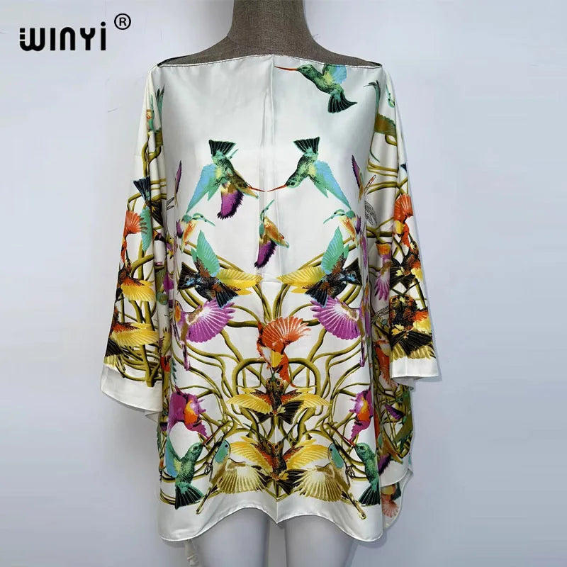 White batwing abaya top featuring a vibrant floral pattern with colorful birds and foliage.
