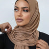 Une femme portant un foulard hijab en jersey beige et des vêtements noirs.