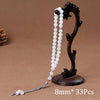 Black agate prayer beads and tassel necklace displayed on a brown background