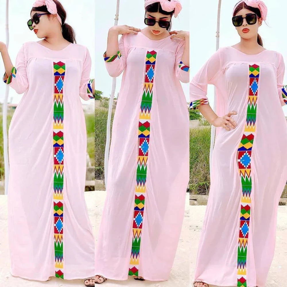Eine Frau modelliert ein pinkes Kaftan-Set mit Stickereien und farbigem Zierrand.