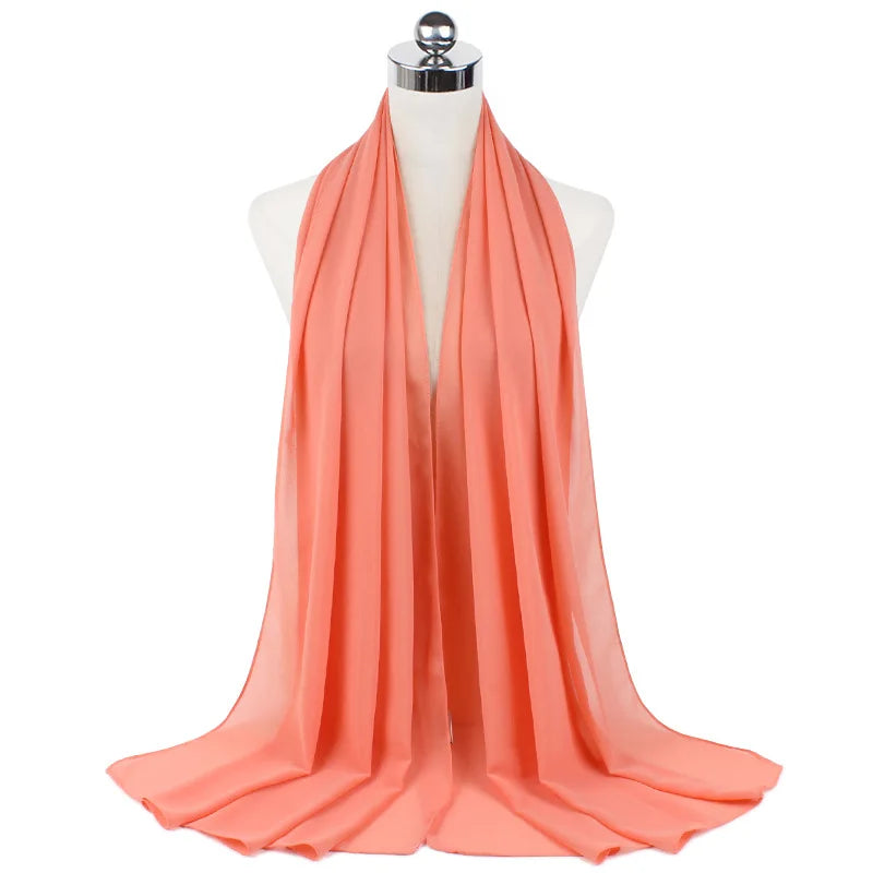 Pañuelo de chifón coral fluido drapeado en un maniquí.