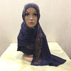 Une femme portant un hijab bleu foncé avec des embellissements de cristaux dorés, présentée sur un mannequin.
