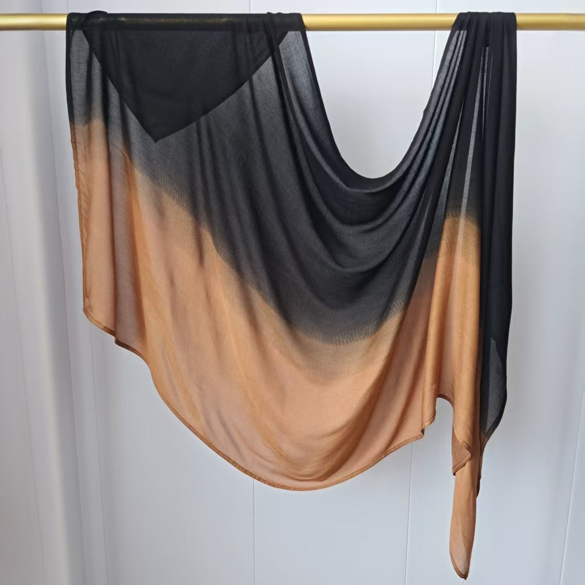 Pañuelo de hijab en gradiente negro y cobre de rayón, colgado en una cuerda de ropa.