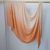Pañuelo de hijab de algodón rayón con degradado ombré en color melocotón o terracota colgado en una percha.