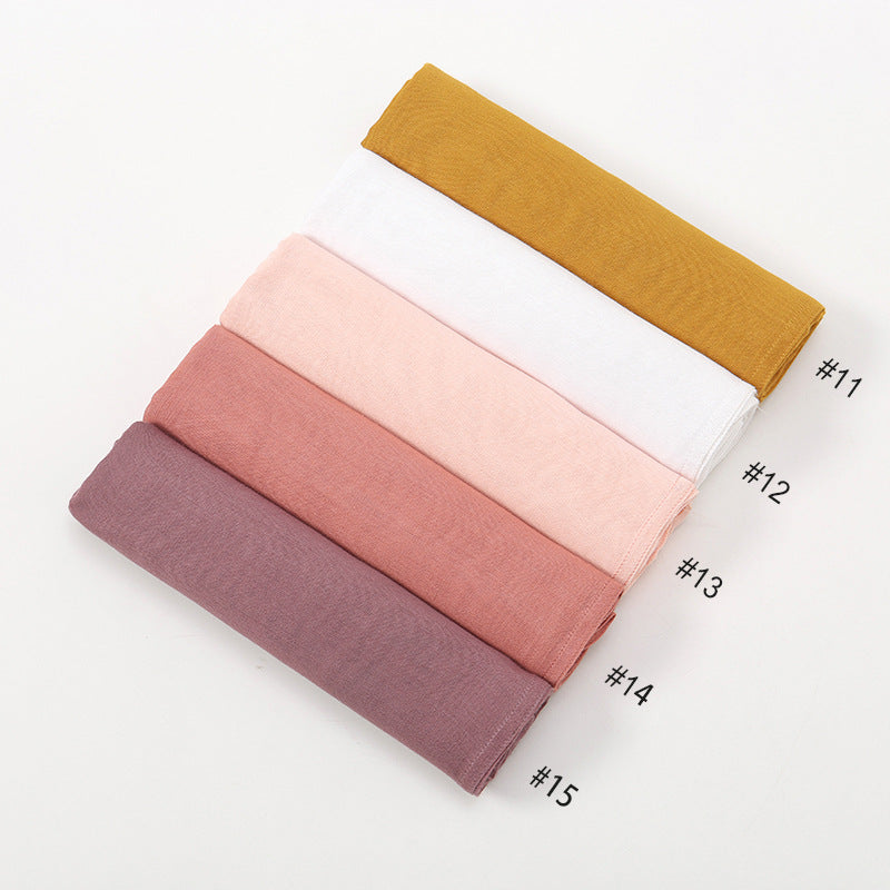 Ein Stapel von fünfzehn gradientfarbenen Rayon-Hijab-Schals, von gelb bis mauve.