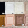 A set of nine folded soft modal rayon hijab fabric squares in various neutral tones including black, white, beige, and pink.