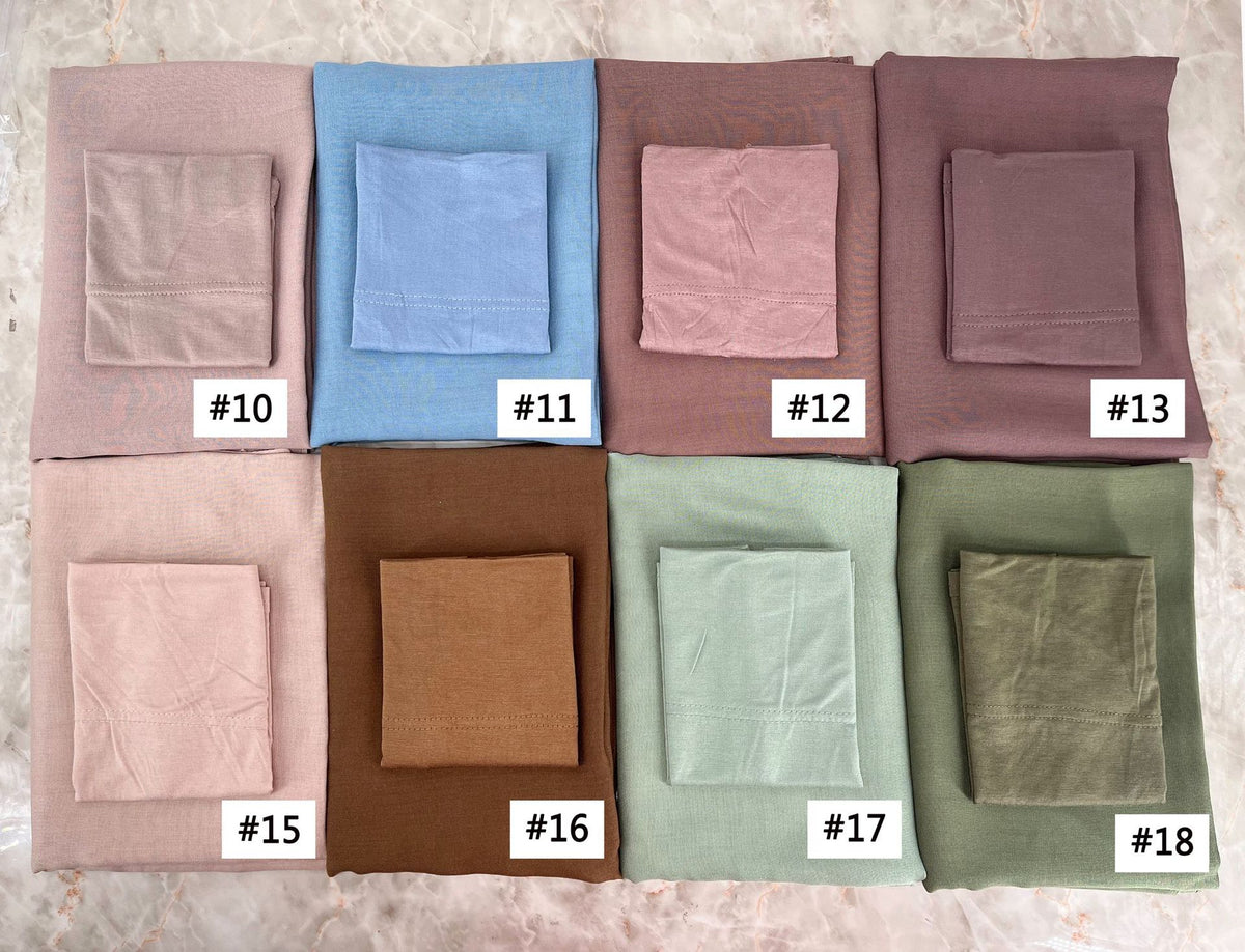 A collection of eighteen folded soft modal rayon hijab sets in various muted earth tones and blues.