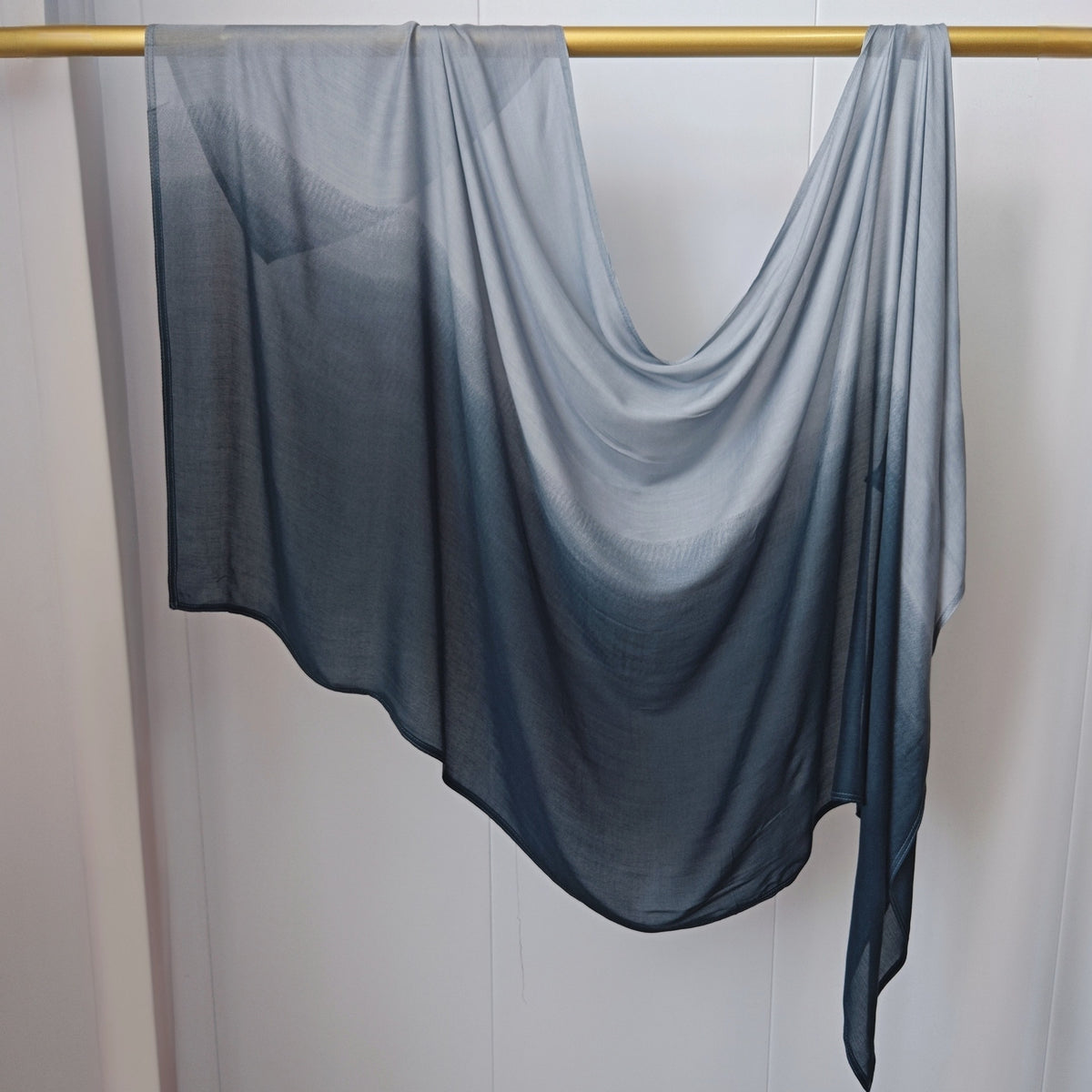 Pañuelo de hijab de algodón rayón con degradado transparente y fluído colgado en una cuerda de ropa.