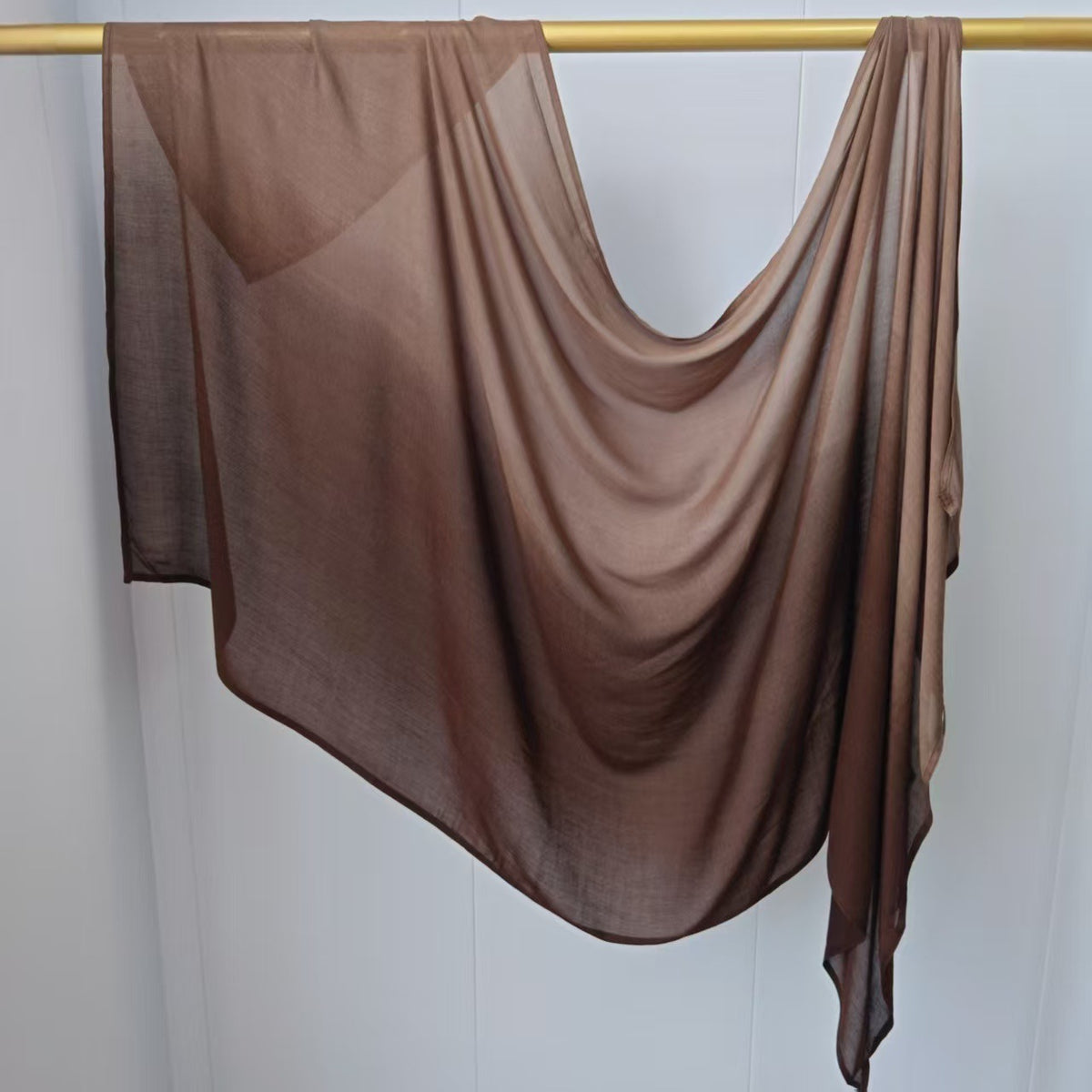 Pañuelo de hijab de algodón rayón en degradado ombré colgado en una varilla de madera.