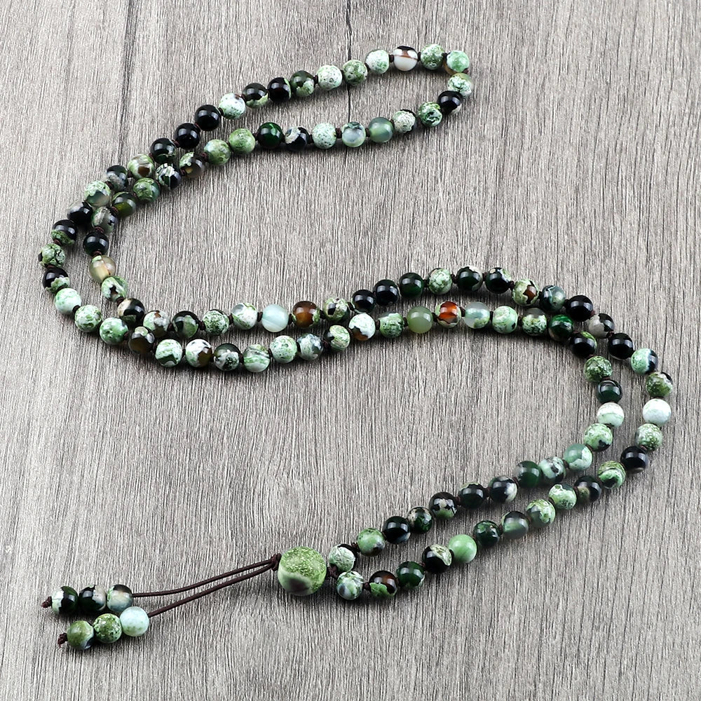 Eine Kette aus natürlichen Steinchen mit grün-schwarz gefleckten Steinen auf einer Holzoberfläche.