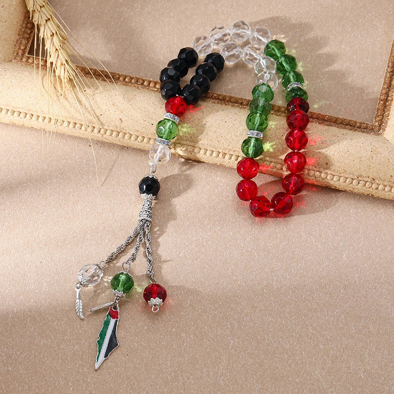 Armband aus Gebetsperlen mit schwarzen, grünen und roten Steinen und einem palästinensischen Flaggenanhänger.