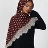 Una mujer vistiendo un hijab de lunares granate con ribete de encaje sobre una blusa negra.